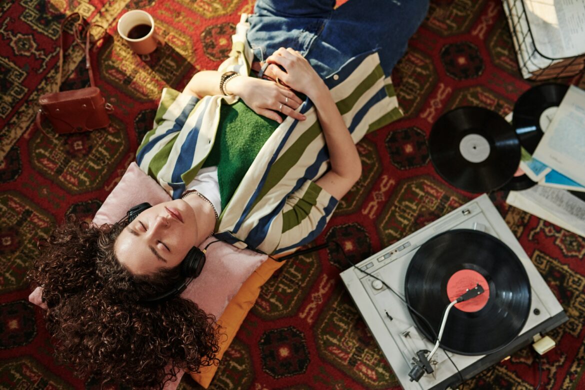 Above angle of young female in casualwear enjoying music in headphones