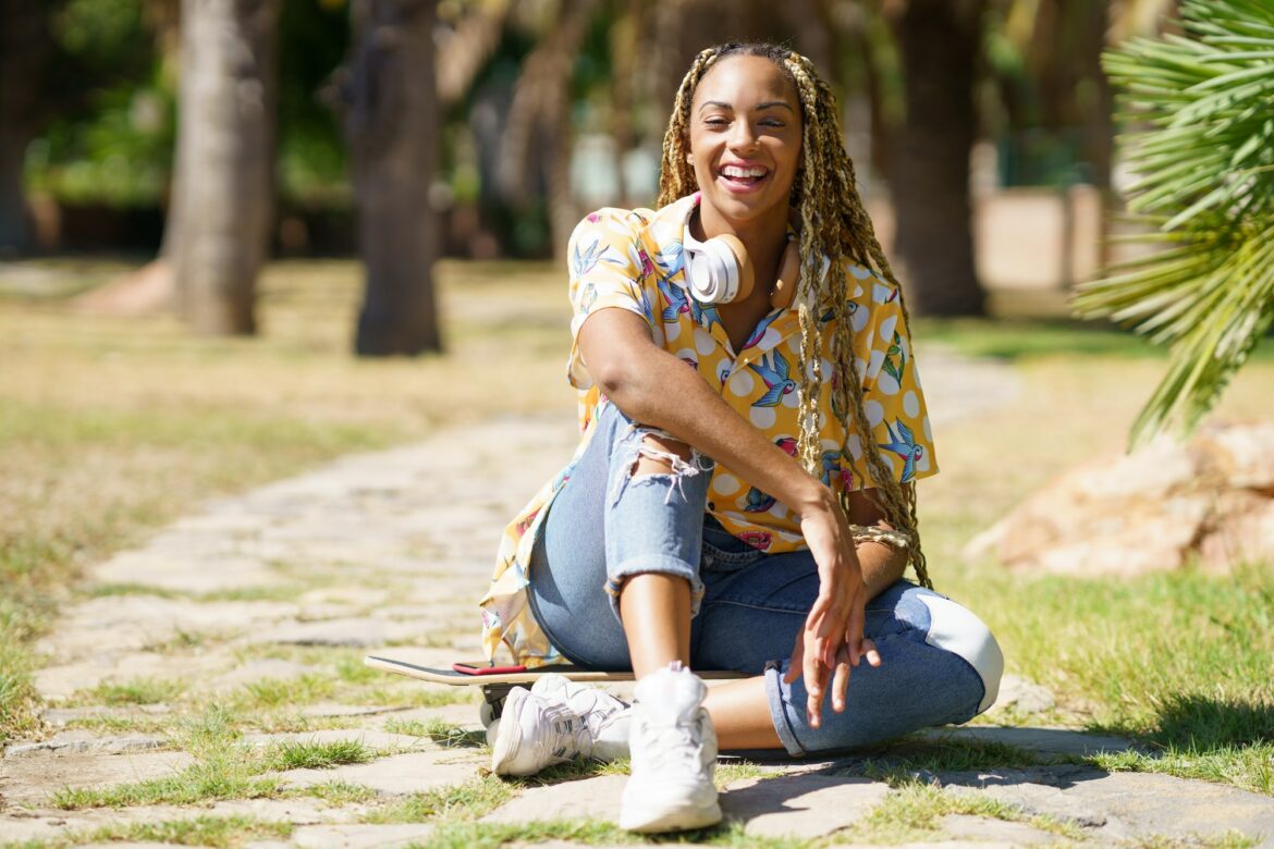 African woman with skateboard relaxing after riding skateboard listening to the music