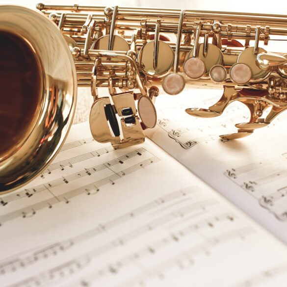 Closeup of a beautiful and shiny golden saxophone lying on music notes
