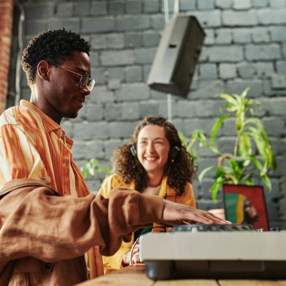 Happy black man adjusting dj controller while creating new music at home
